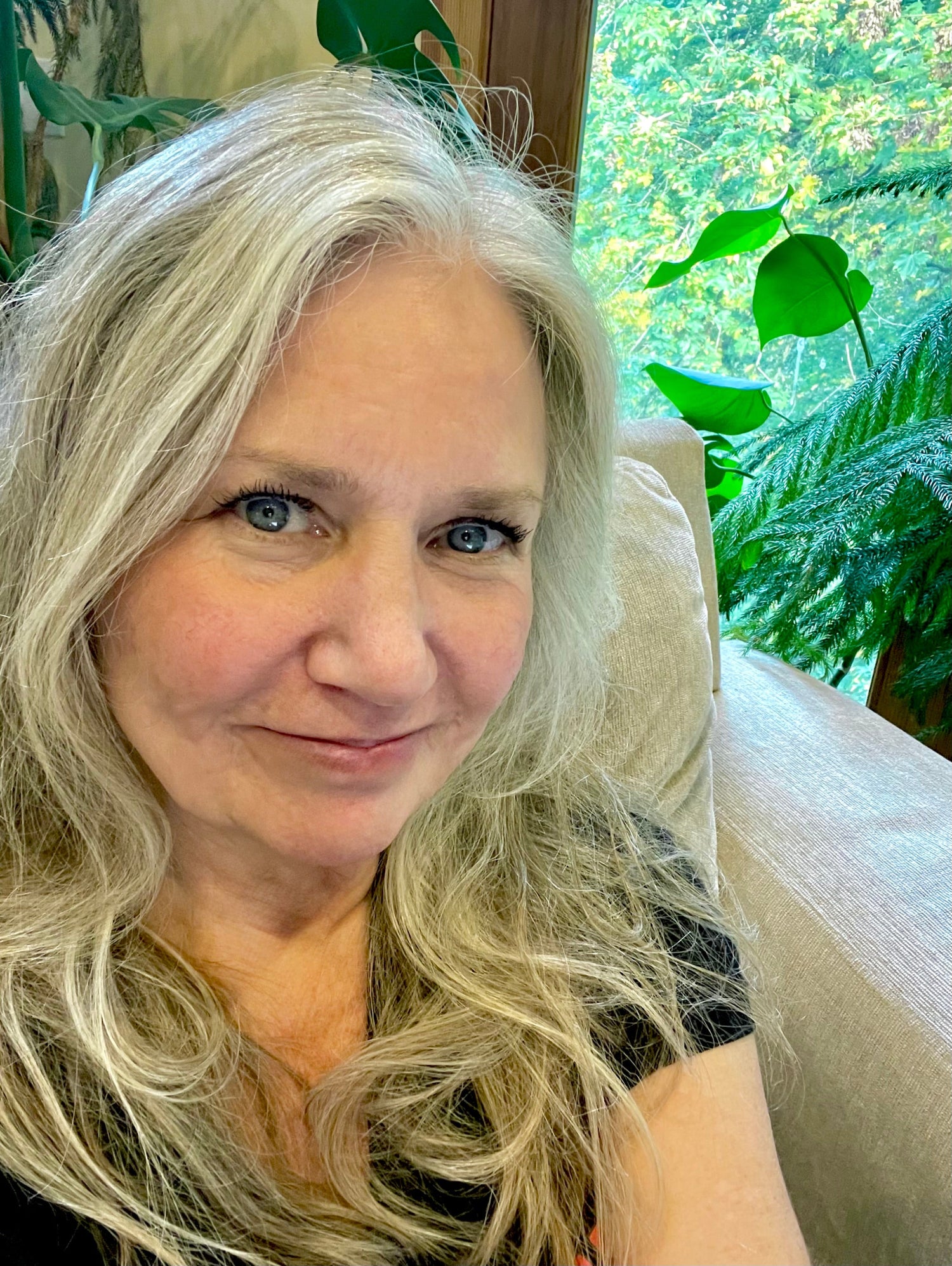 Woman with blonde hair sitting in a room with green plants