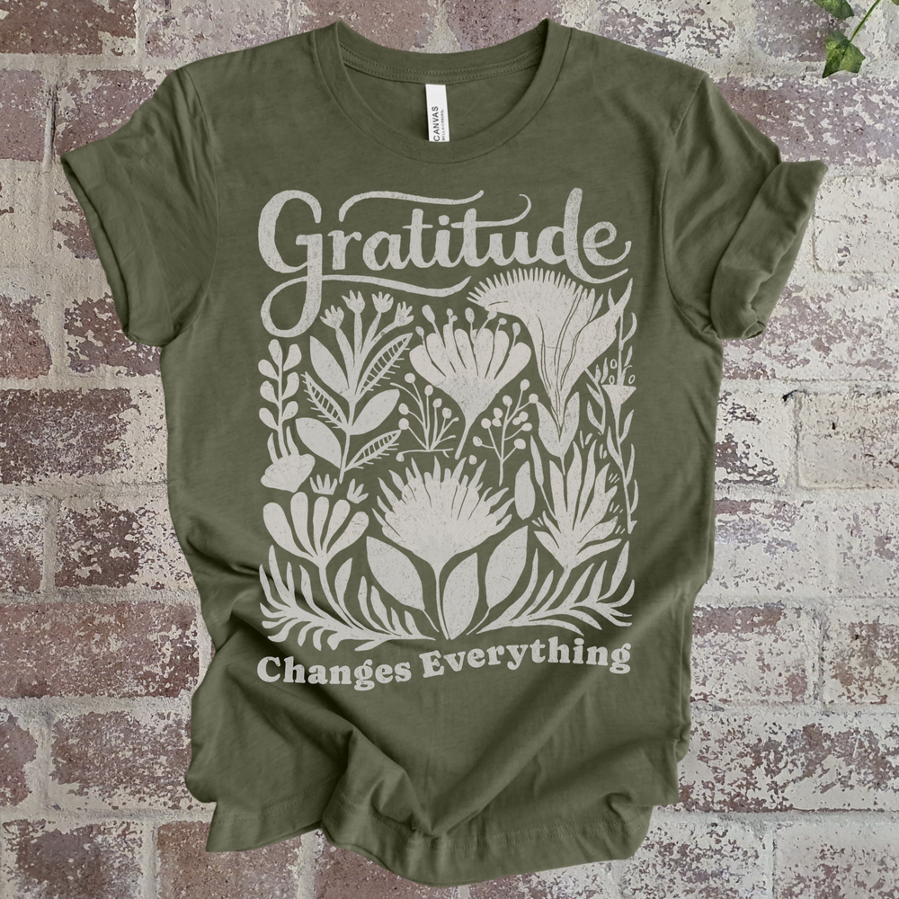 Green t-shirt with 'Gratitude Changes Everything' design on a brick background