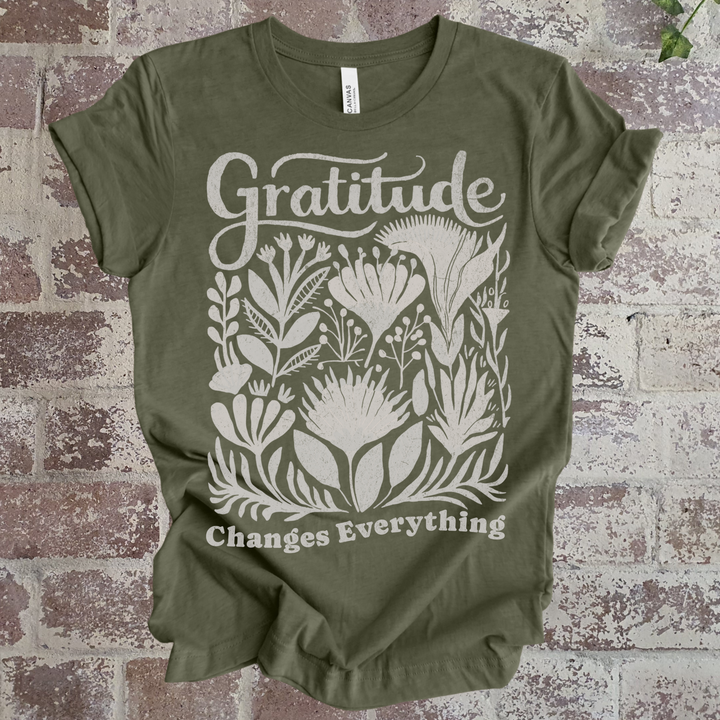 Green t-shirt with 'Gratitude Changes Everything' design on a brick background