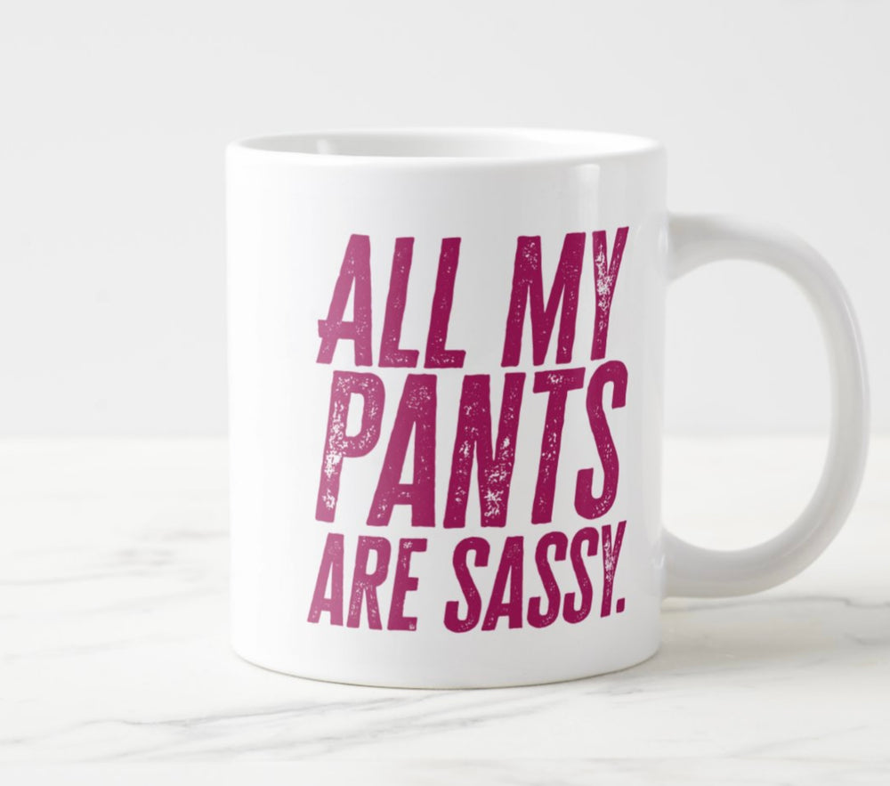 Photo of large white mug, with hot pink tet saying “All My Pants Are Sassy”.