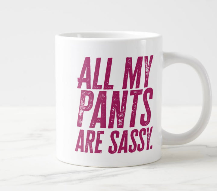 Photo of large white mug, with hot pink tet saying “All My Pants Are Sassy”.