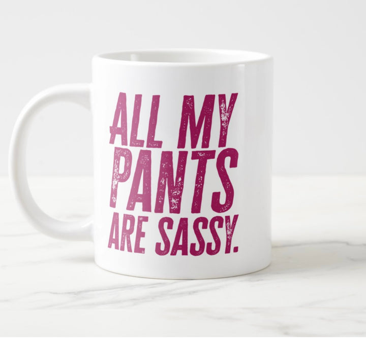 Photo of large white mug, with hot pink tet saying “All My Pants Are Sassy”.