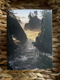 Scenic view of closeup of rough Pacific coastal cove waters on a card, on a woven mat background.