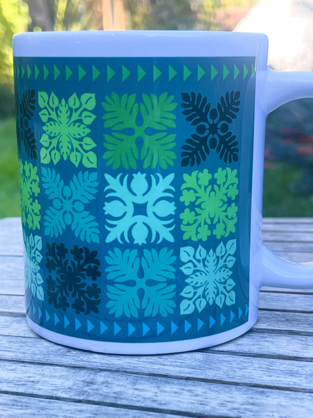 Mug with geometric Hawaiian quilt pattern on a wooden surface