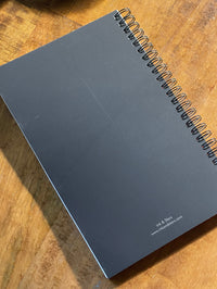 Black spiral-bound notebook on a wooden surface