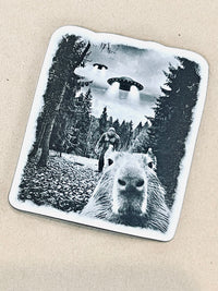 Sticker with capybara, UFO, and Sasquatch on a beige background