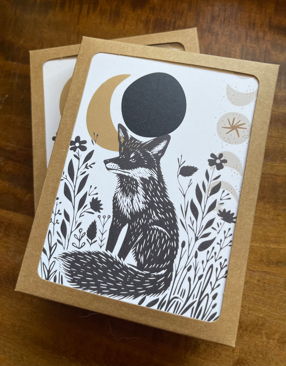 Stacked boxes of greeting cards featuring a fox and crescent moon graphic.