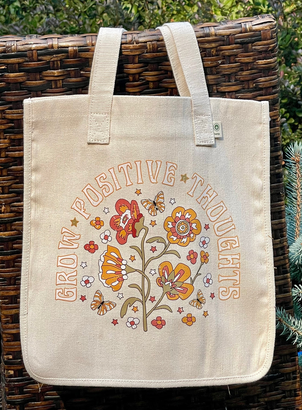 Beige tote bag with flowery “Grow Positive Thoughts” graphic.