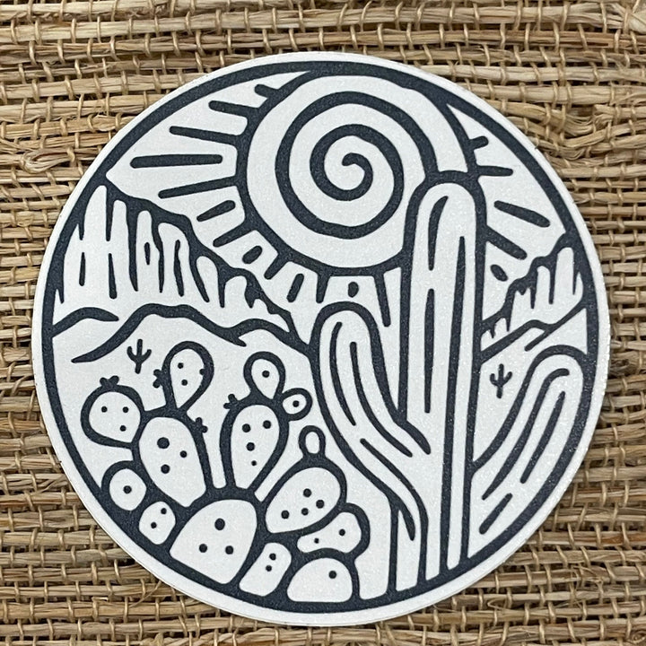 Round sticker with outline drawing of desert plants.