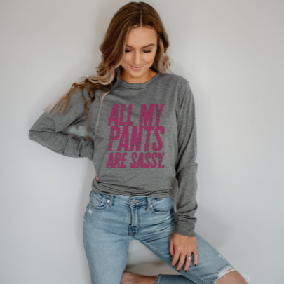 Young woman wearing a long sleeve light grey tee with “All My Pants Are Sassy” graphic.
