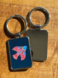 Keychain with a colorful red bird design on a wooden surface