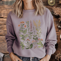 Person wearing a purple sweatshirt with floral designs in front of a wooden surface