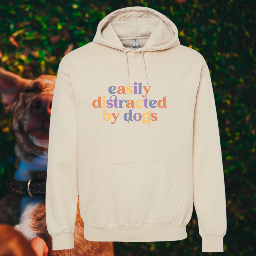“Easily Distracted By Dogs” graphic on cream colored hooded sweatshirt.